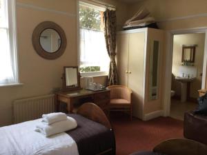 
a hotel room with a bed, chair, mirror and a window at THE RAILWAY HOTEL in Faversham
