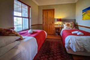 
a bed room with two beds and a desk at Berluda Farmhouse and Cottages in Oudtshoorn
