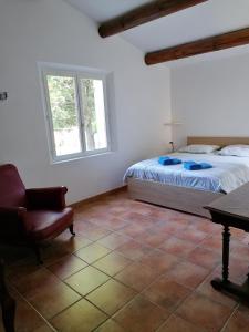 een slaapkamer met een bed, een stoel en een tafel bij mas cantarello in Rognes