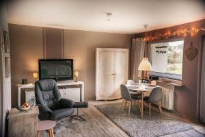 a living room with a table and chairs and a television at Harzgeiss in Hohegeiß