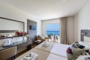 a hotel room with a bed and a desk with a view at Queens Bay Hotel in Paphos