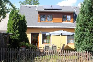 ein gelbes Haus mit einem Zaun und einem Regenschirm in der Unterkunft Ferienhaus Krawulski in Hohnstein