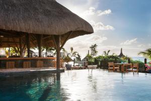 a resort with a swimming pool with a straw roof at Veranda Pointe Aux Biches Hotel & Spa in Trou aux Biches