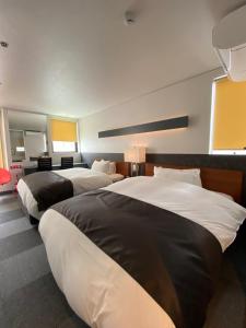 2 Betten in einem Hotelzimmer in Weiß und Schwarz in der Unterkunft Hotel 草石庵 in Osaka