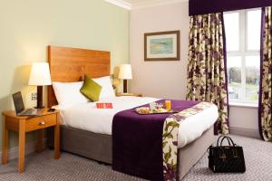 
a hotel room with a bed and a dresser at Maldron Hotel & Leisure Centre, Oranmore Galway in Oranmore
