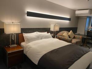1 dormitorio con 1 cama grande y 1 silla en Hotel 草石庵 en Osaka