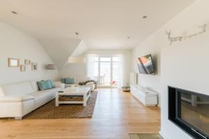ein Wohnzimmer mit einem weißen Sofa und einem Fernseher in der Unterkunft Belle Maison - Das kleine Hotel in Werbach