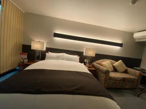 una camera con un grande letto e una sedia di Hotel 草石庵 ad Osaka
