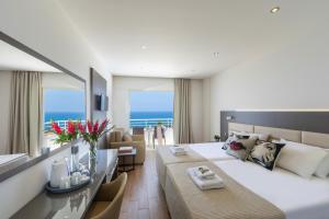 a bedroom with a large bed and a living room at Queens Bay Hotel in Paphos