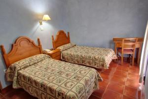 um quarto de hotel com duas camas e uma mesa em Hotel Rural Ocell Francolí em Espluga de Francolí