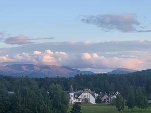 a group of houses in a field with mountains in the background at Carrbridge Hotel in Carrbridge