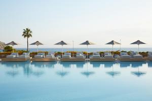 a pool with lounge chairs and umbrellas on the beach at Vincci EverEden in Anavyssos