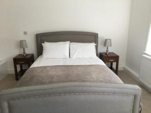 Beautiful 1 BED Serviced APARTMENT COBHAM Town Centre في كوبهام: غرفة نوم مع سرير مع مواقف ليلتين