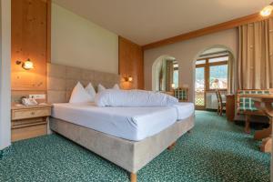 a bedroom with a large bed and a desk at Apparthotel Thalerhof in Mayrhofen