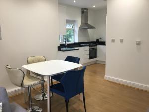 Beautiful 1 BED Serviced APARTMENT COBHAM Town Centre في كوبهام: مطبخ بطاولة بيضاء وكراسي زرقاء