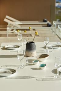 a table with glasses and a vase with flowers on it at Vincci EverEden in Anavyssos