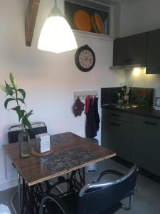 een keuken met een tafel met stoelen en een klok aan de muur bij Tiny House Tulp in Oudesluis