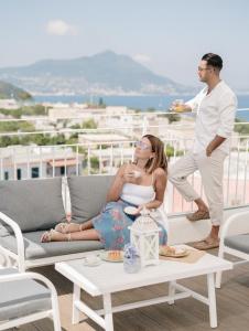 Eine Frau auf einer Couch auf einem Balkon mit einem Mann in der Unterkunft Le Volte Procida Home in Procida