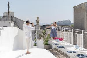 a man taking a picture of a woman on a balcony at Le Volte Procida Home in Procida