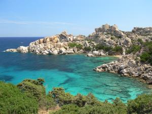 an island in the ocean with blue water and rocks at Rena Garden Apartments in Rena Majore