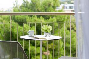 a table with a cup and a vase of flowers on a balcony at Vincci EverEden in Anavyssos