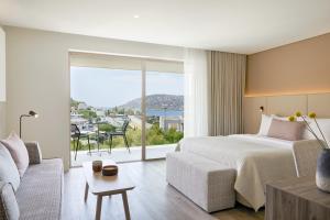 a bedroom with a bed and a couch and a large window at Vincci EverEden in Anavyssos