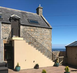 a stone house with a staircase on the side of it at Skerry View - Overlooking the Moray Firth - close to Beaches, Harbour, Shops and Restaurants in Lossiemouth