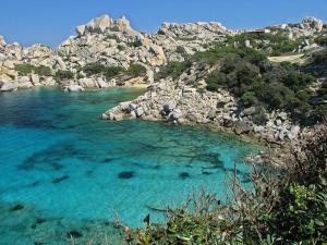 a beach with blue water and a rocky shore at Rena Garden Apartments in Rena Majore