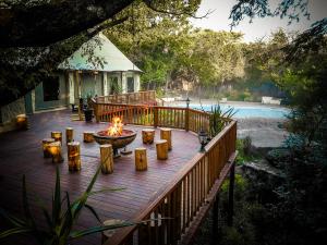 a fire pit on a wooden deck next to a pool at Kruger Adventure Lodge in Hazyview