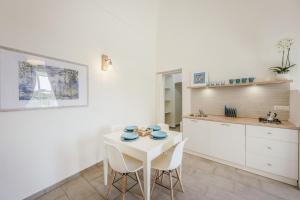 a white kitchen with a white table and chairs at Le Volte Procida Home in Procida