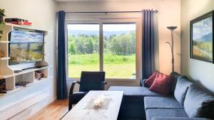 een woonkamer met een bank, een tafel en een raam bij Geilolia Ferieleiligheter in Geilo