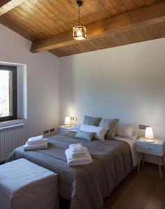 Habitación con 2 camas, paredes blancas y techos de madera. en Casa Cal Saboya en L'Espunyola