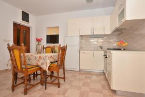 eine Küche mit einem Tisch und Stühlen sowie einem Kühlschrank in der Unterkunft Apartments Jovic in Makarska