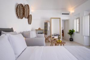 a white bedroom with a bed and a couch at Radiant Santorini in Mesaria