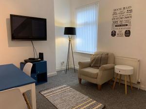 a living room with a chair and a flat screen tv at Bright, Comfortable Home, Convenient for City Centre in Liverpool