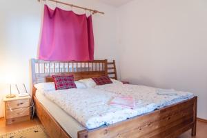 a bedroom with a wooden bed with a pink curtain at TATRYSTAY Apartment Milo in Nový Smokovec