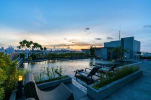 曼谷的住宿－De Botan Srinakarin Hotel & Residence，屋顶庭院配有椅子,黄昏时分有河流