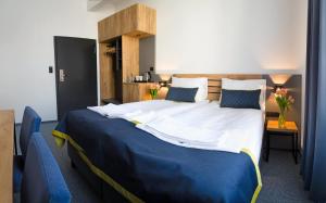 a bedroom with a large bed with blue and white sheets at Hotel Mokotów in Warsaw