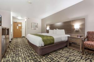 a hotel room with a large bed and a chair at Quality Inn & Suites Omaha Chalco in Omaha +21 photos