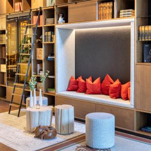 a bench with orange pillows on it in a library at MOSAIC HOUSE Design Hotel in Prague