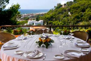 a table with plates and wine glasses and a view of the ocean at Gran Hotel Rey Don Jaime in Castelldefels