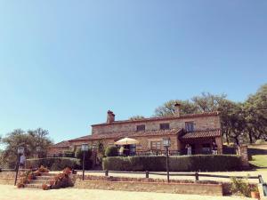 una gran casa de piedra con una valla delante en Apartamentos Rurales La Macera ****, en Valencia de Alcántara
