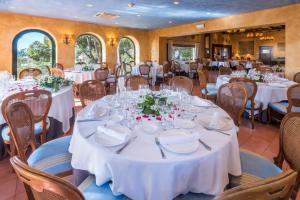 uma sala de jantar com mesas e cadeiras brancas em Gran Hotel Rey Don Jaime em Castelldefels