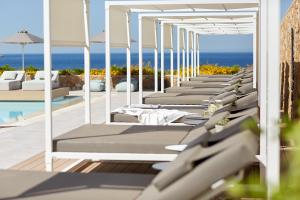 a row of chaise lounge chairs next to a pool at Vincci EverEden in Anavyssos