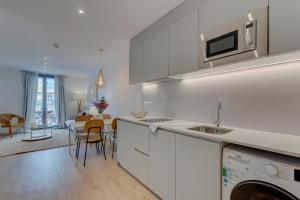 a kitchen with white cabinets and a dining room at Happy Apartments in Barcelona