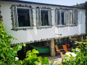 uma casa com janelas e cadeiras num quintal em Pensión Santa Rosa em Samos