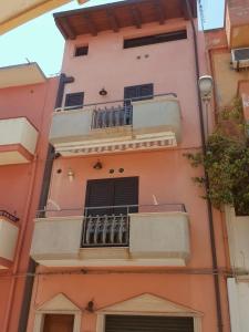 a pink building with a balcony on it at Appartamento moderno in Le Castella