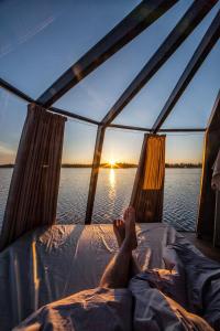 a person laying on a bed on a boat in the water at Arctic Lake Experience Oulujärvi Igloos in Kajaani