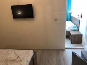 a room with a bed and a flat screen tv on the wall at Pensiunea Paradis in Băile Herculane