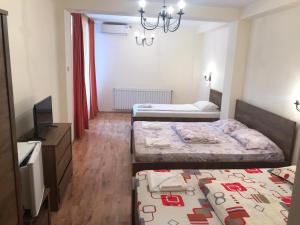 a hotel room with two beds and a television at Pensiunea Paradis in Băile Herculane +14 photos